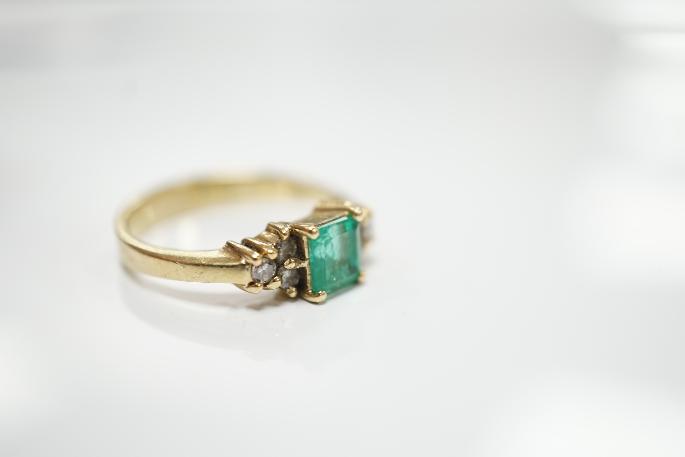 A modern 18k, emerald and diamond set cluster ring, size N, gross weight 3.8 grams.